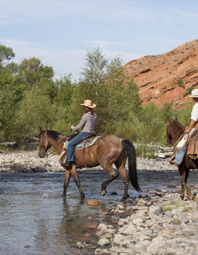 3 Riders on Horseback Crossing the East Fork of the Wind River with red cliffs in the background - Lazy L&B Guest Ranch Wyoming